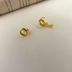 Detail of polished gold-plated S925 sterling silver hoop earrings on a minimalist surface