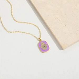 Macro view of purple enamel Hamsa Hand pendant with zircon inlay on a golden chain