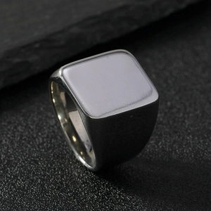 Macro shot of silver square signet ring on black textured stone background