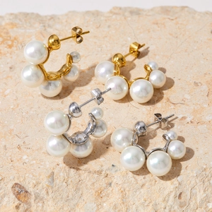 Elegant C-shaped pearl hoop earrings in gold and silver finish on natural stone