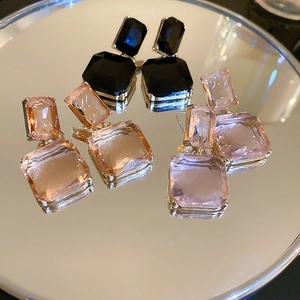 Detailed view of geometric square crystal earrings in black, champagne, and lavender hues