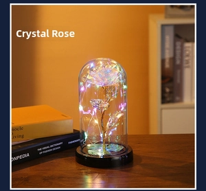 Detail of crystal glass rose in glass dome with colorful LED fairy lights and black base
