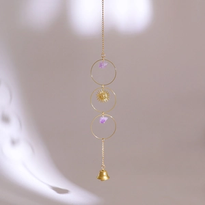 Close-up of golden sun face charm and natural purple crystal stones on a boho wind chime