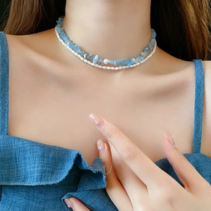 Détail d'un collier à deux rangs avec éclats de pierre bleue et perles blanches