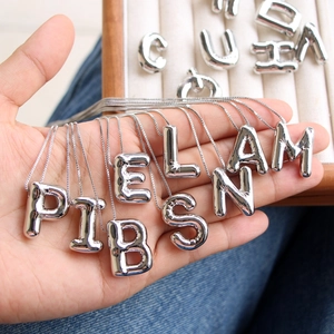 Detailed macro of 3D balloon letter pendant with polished silver finish and box chain