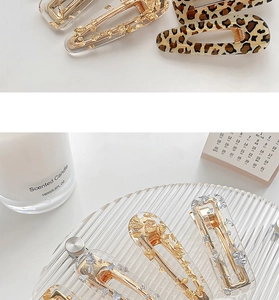 Detail of leopard print and foil resin hair clips on a minimalist lifestyle setting