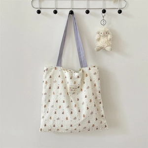 Close-up of cream canvas tote bag with brown bear patterns and purple shoulder strap