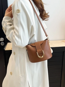 Retro brown leather bucket bag with gold U-shaped buckle shown on model in studio