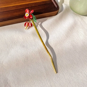 Detailed close-up of a floral hair pin with red petals, pearl beads and tassels on white fabric