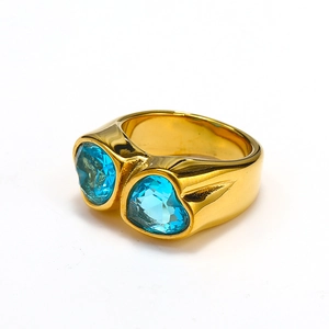 Close-up of golden wide-band ring with double light blue heart-shaped gemstones