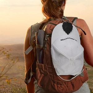 Close-up of black leaf-shaped PU leather magnetic hat clip attached to a travel backpack