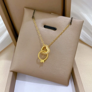 Collana dorata con pendente a cuore e anello intrecciati in un astuccio per gioielli