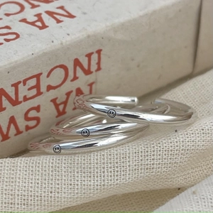 Detailed macro view of three adjustable 925 silver smiley face rings on woven texture