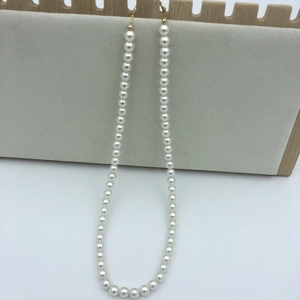 Detailed close-up of high-luster cream white pearls on a minimalist necklace with gold clasp