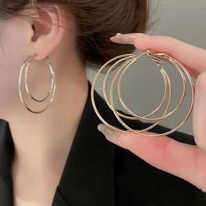 Detail of layered double circular polished hoop earrings shown on model and held by hand
