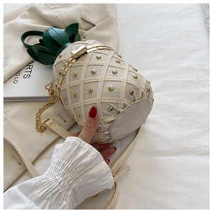 Close-up of a pineapple-shaped shoulder bag with gold studs and green leaf details