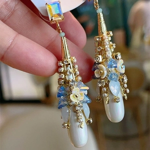 Bohemian drop earrings with blue crystals and white floral details in gold finish