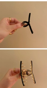Detailed close-up showing the side and teeth of a black and gold metal hair claw clip