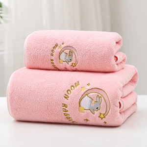 Detail of pink coral fleece towel featuring moon rabbit embroidery and soft plush texture