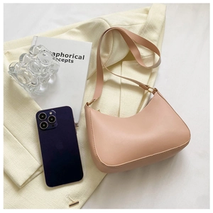 Detailed view of dusty pink half-moon shoulder bag styled on a beige blazer background