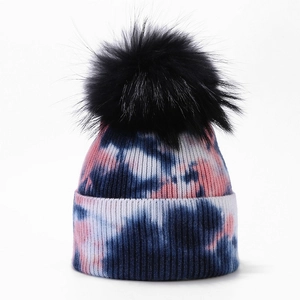Women's pink and navy tie-dye knit beanie featuring a large black faux fur pom-pom detail