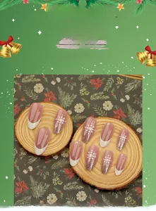 Close-up of French white tip nails with snowflake patterns and gold glitter on wood