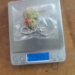 Detail of a sparkling crystal duck keychain pendant with gold rhinestones on a scale