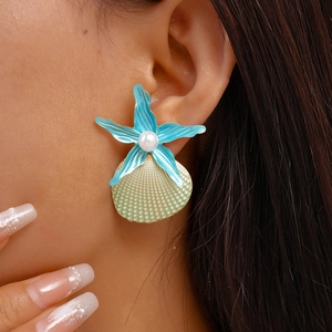 Close-up of beach-style starfish and seashell earrings with pearls on model ear