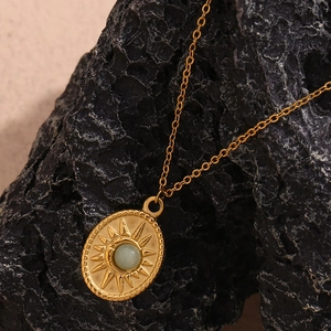 Macro shot of 18K gold plated sunburst oval pendant necklace with green natural stone