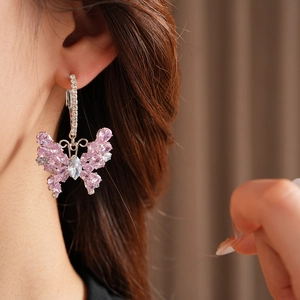 Close-up of pink zircon butterfly earrings featuring silver metal and sparkling stones