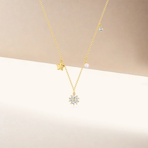 Detail of gold necklace featuring zircon clover, star, white pearl and sparkling crystals