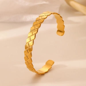 Detailed side view of golden open bangle featuring a diamond weave textured surface
