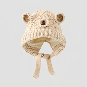 Close-up of beige knit bear ear beanie for kids showing warm lining and chin straps