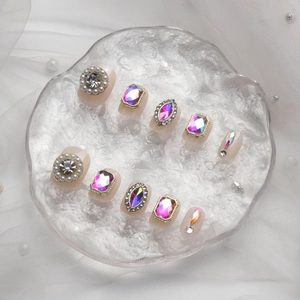 Faux ongles luxueux avec perles et cristaux irisés sur une base rose nude doux