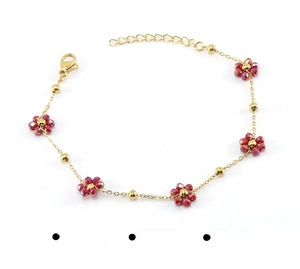 Macro detail of gold stainless steel flower bracelet with red faceted crystal beads