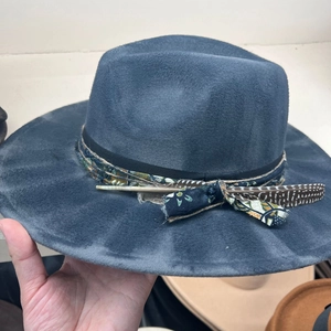 Detail of felt fedora hat showing ethnic print ribbon and natural feather decoration