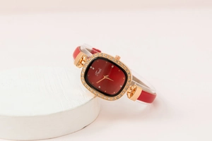 Detail of red leather strap and gold rectangular watch case with rhinestone bezel