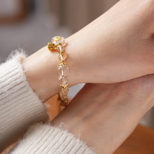 Detail of Citrine and White Quartz beaded bracelet with gold charm on a woman's wrist