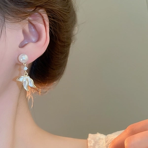 Gros plan de boucles d'oreilles perles dorées avec pendentifs pétales sur un mannequin