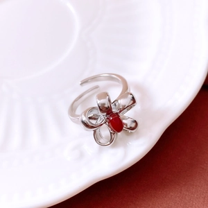 Detailed macro view of vintage silver bow ring with red gemstone on white ceramic plate