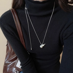 Dettaglio della collana con ciondolo a zucca in argento spazzolato su maglione nero