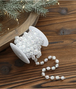 Close-up of iridescent plastic bead garland on a white spool for Christmas tree decor