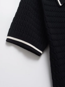 Detail showing the cable knit texture and contrasting white stripes on the black polo shirt