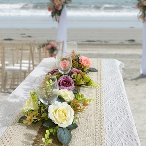 Artificial flower table runner with roses for wedding decor on a scenic beach table
