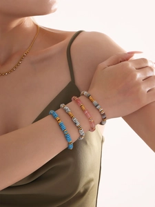 Close-up of model wearing stacked natural stone bead bracelets with 18k gold plated chains