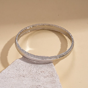Macro shot of silver textured bangle with horizontal grain on a natural stone base