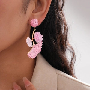 Detail of pink raffia floral drop earring on model in beige blazer close-up view