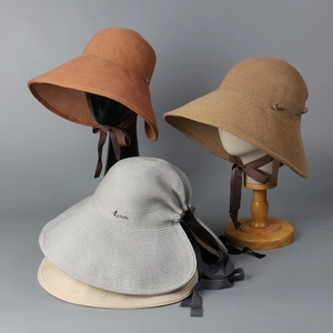 Detailed view of sun hat weaving texture with metal logo and adjustable ribbon bow tie