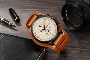 Detail view of large white dial watch with brown leather strap on office desk