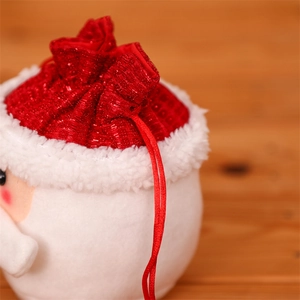 Close-up of red sequin Santa Claus drawstring gift bag on a warm wooden background